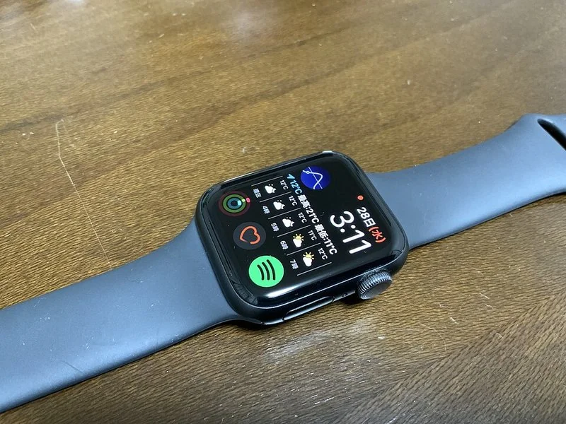 como ahorrar bateria apple watch, Apple Watch con esfera oscura de complicaciones de clima, actividad y música sobre un escritorio