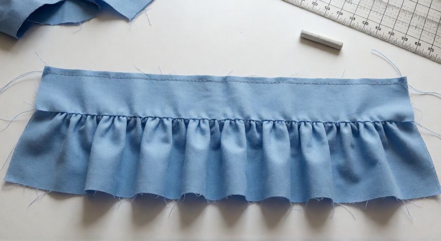 como coser fruncido, Tira de tela con puntada larga cosida y fruncido parcialmente formado sobre tapete de corte