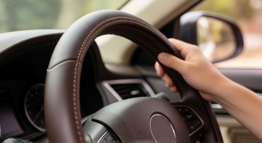 como coser funda de volante, Funda de volante de cuero oscuro montándose en el volante de un coche