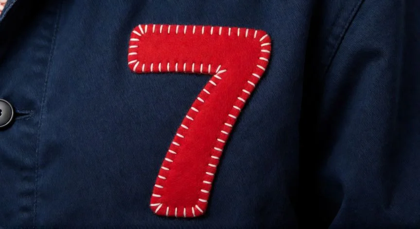 como coser un 7 en una campera, Número 7 de fieltro rojo cosido con puntada espagatí en el pecho de una campera azul marino