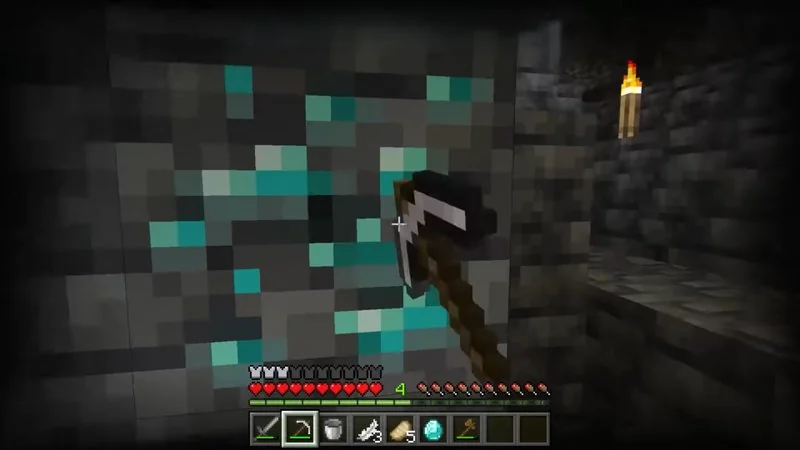 Jugador minando diamantes en una cueva oscura de Minecraft con pico y antorcha
