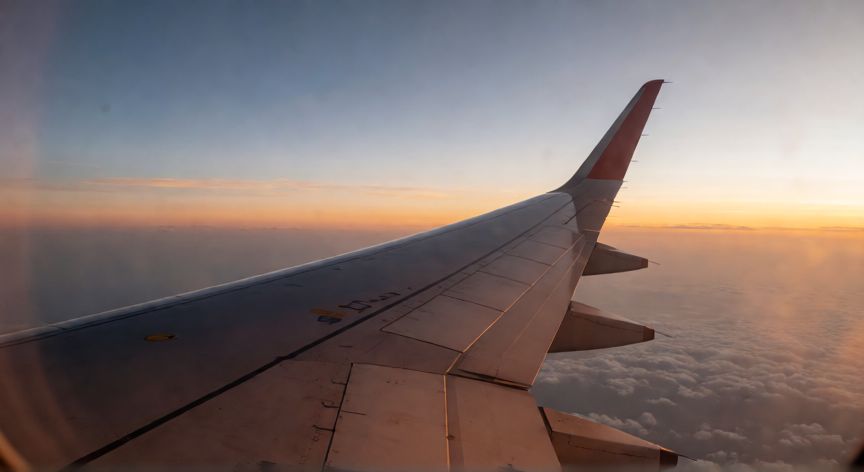 como encontrar vuelos baratos de última hora, Vista de la ventana de un avión al atardecer