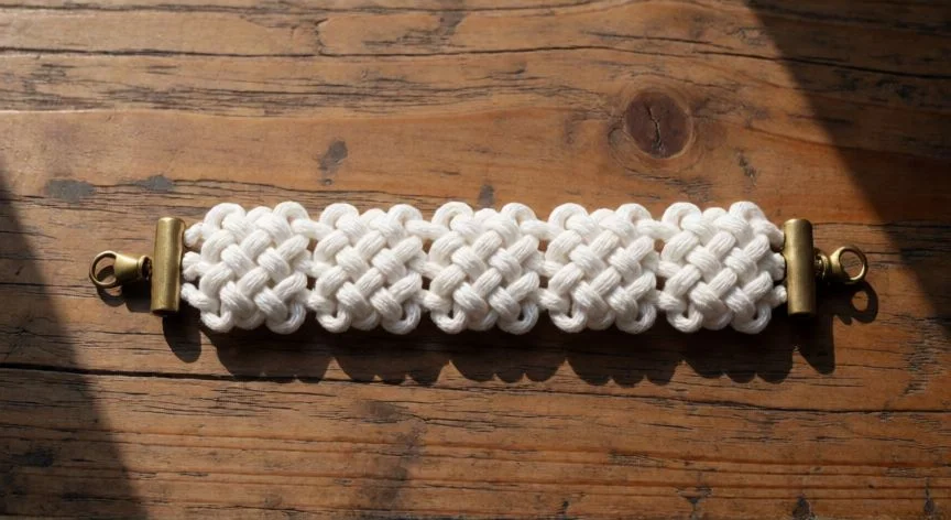 como hacer 5 nudos para pulseras, Pulsera artesanal terminada con cinco nudos cuadrados sobre madera