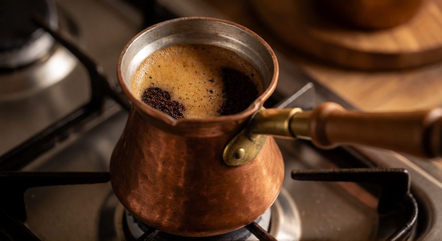 como hacer cafe a la turca, Cazuela de cobre tradicional con café turco cociendose suavemente