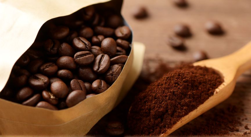 como hacer cafe arabe, Granos de café arábica recién tostados y molienda media en cuchara de madera