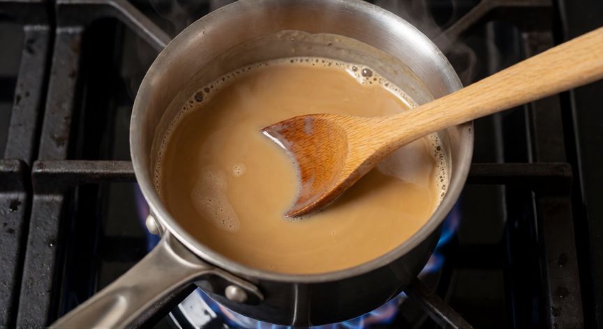 como hacer cafe lechero, Proceso de cocción de café y leche en una olla pequeña sobre fuego lento