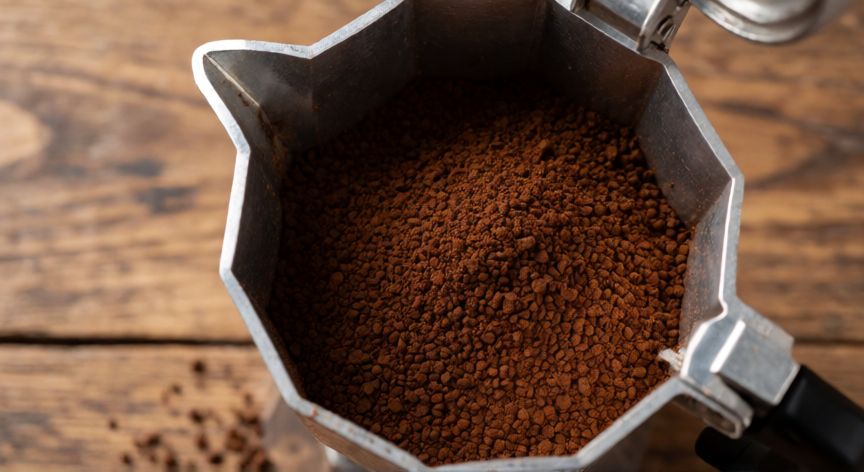 como hacer cafe rico en cafetera italiana, Café molido de textura media-fina llenando el filtro de la cafetera italiana