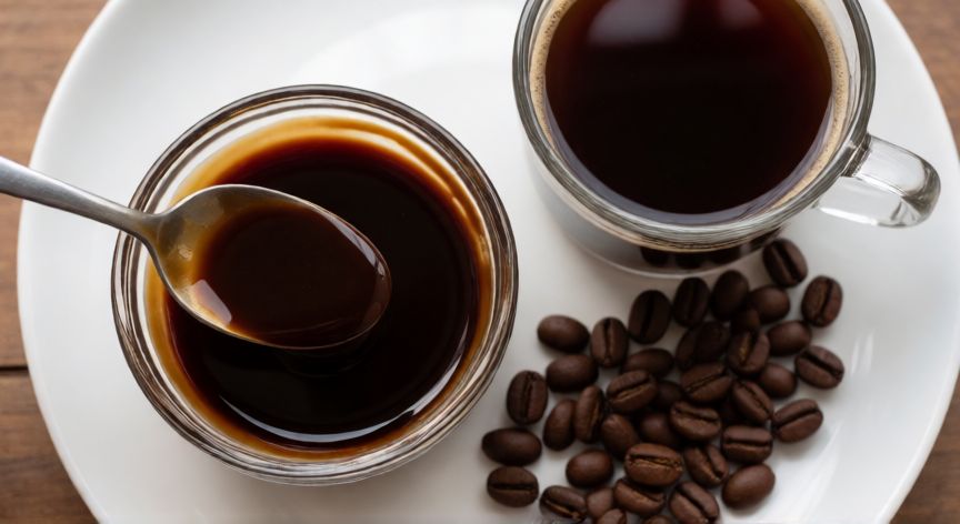 como hacer crema de cafe con agua y azucar, Copa de crema de café con cuchara y taza de café al lado