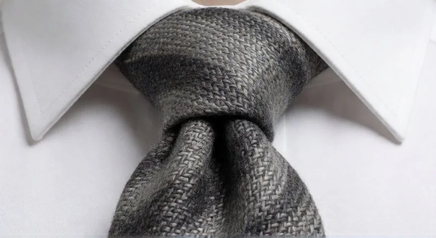 como hacer el nudo de la corbata, Detalle de un nudo Windsor simétrico en corbata gris sobre camisa blanca