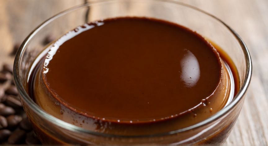 como hacer flan de café sin nata y sin horno, Flan de café brillante en un bol de cristal sobre mesa de madera