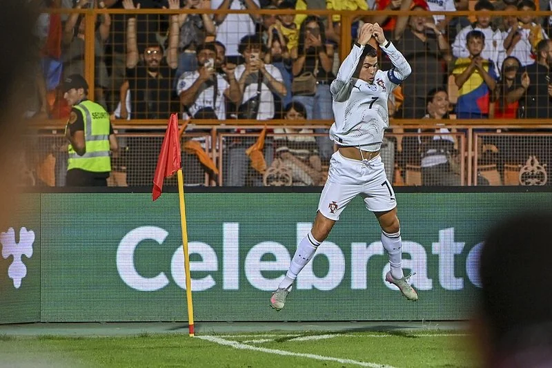 Jugador de fútbol celebrando un gol corriendo hacia la cámara en un estadio lleno