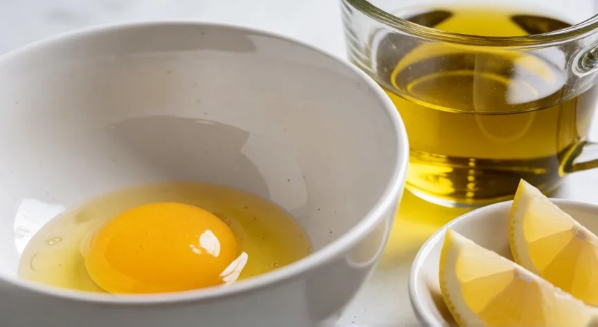 Ingredientes para mayonesa casera: yemas de huevo, aceite de oliva y limón sobre una mesa de cocina.