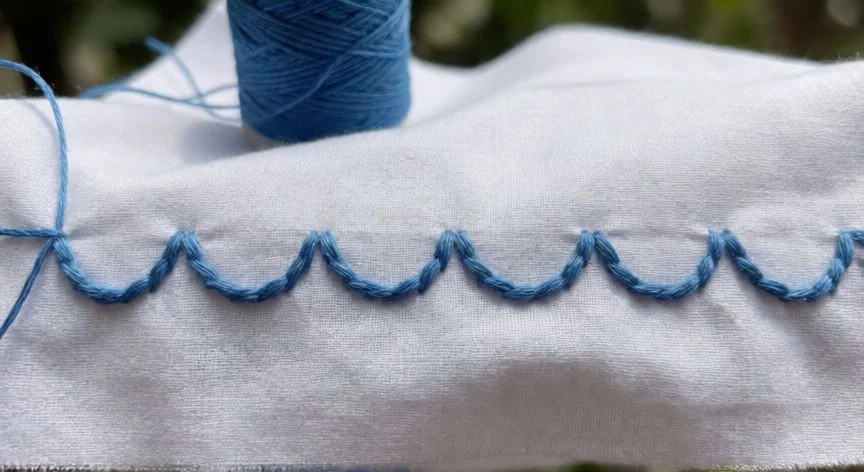 como hacer punto feston bordado, Servilleta terminada con borde de punto festón en hilo turquesa sobre tela blanca