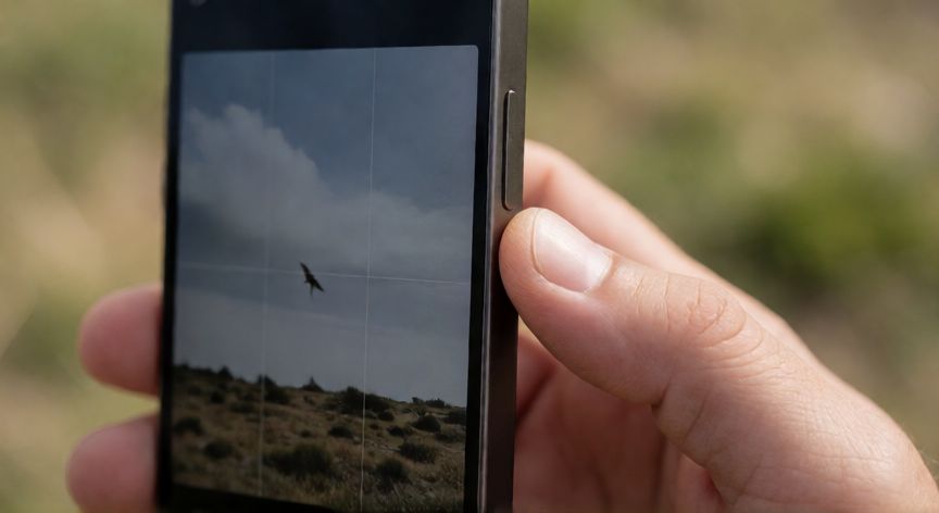 como hacer zoom con el nuevo boton de iphone, Mano presionando el botón Acciòn del iPhone 16 para activar zoom de cámara