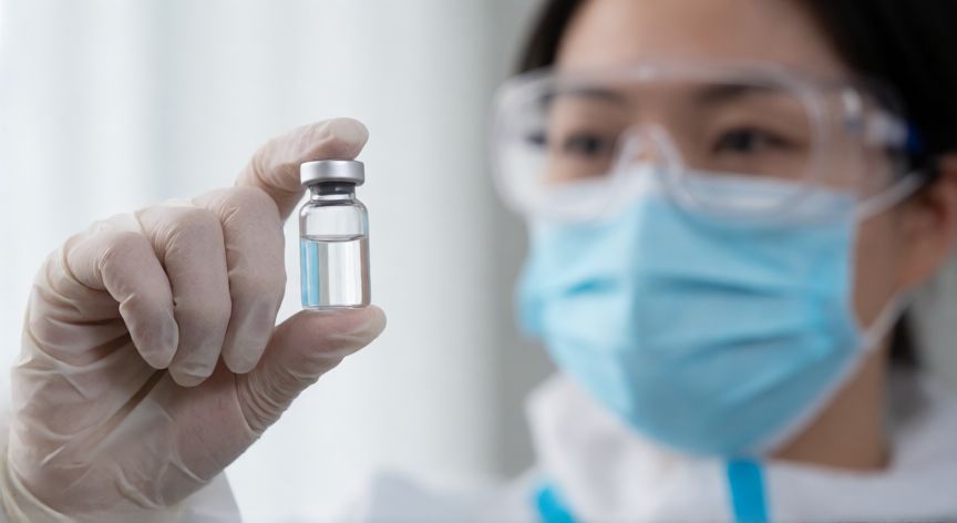 covid 19 brote, Profesional de la salud sosteniendo una vacuna contra el coronavirus en un entorno clínico moderno