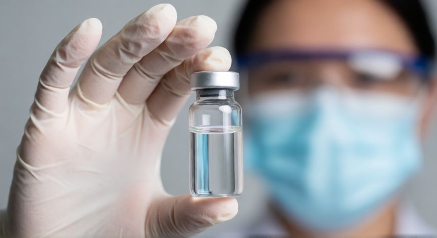 covid 19 update 2025, Vial médico en mano guanteada en entorno de laboratorio