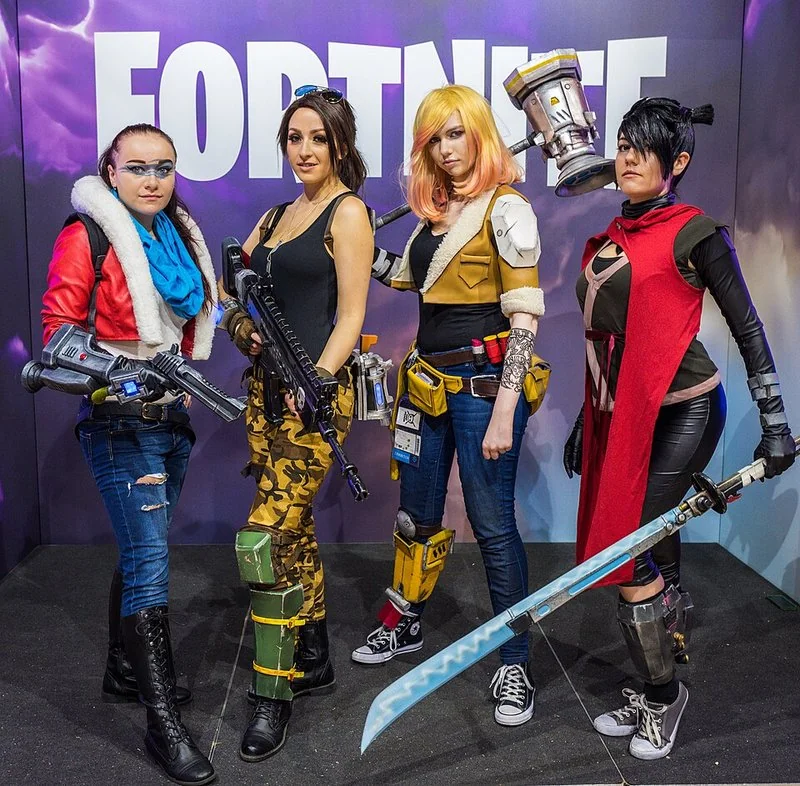 cual es el mejor regalo para abrir en fortnite, Cosplayers de Fortnite con picos frente al logotipo del juego en Gamescom