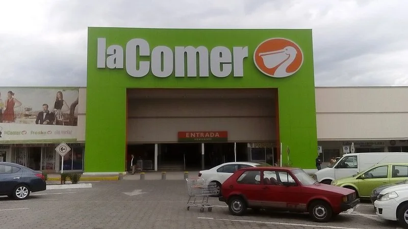 Fachada verde del hipermercado La Comer en Querétaro con pelícano y carteles de Fresko y City Market