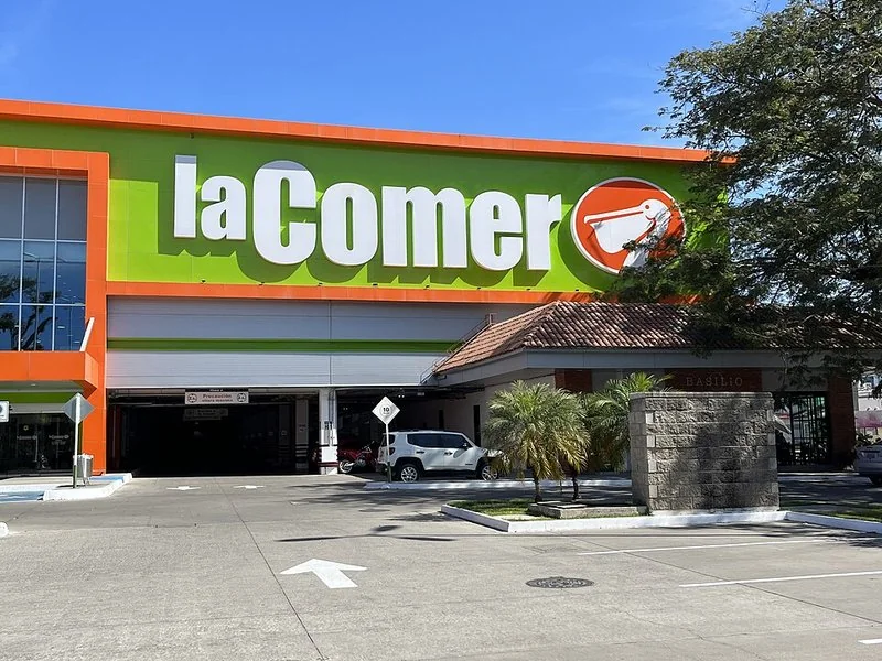 diferencia entre city market y la.comer, Entrada y estacionamiento de una tienda La Comer en Puerto Vallarta, Jalisco, con logotipo verde y naranja