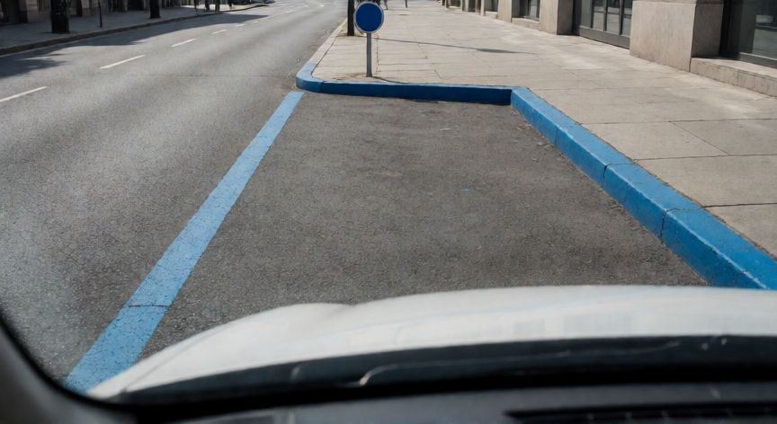 Vista de una plaza de aparcamiento en zona azul con línea y bordillo azules
