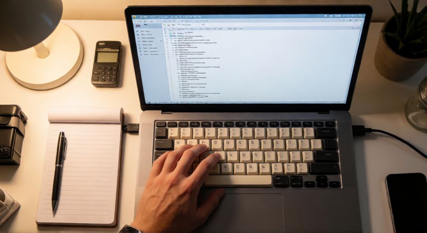 excel en tsv, Vista cenital de un escritorio con portátil mostrando datos TSV en un editor de texto y teclado mecánico