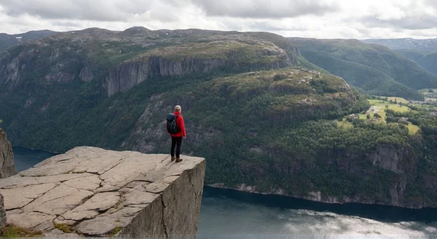 mejor forma de ver los fiordos noruegos, Senderista en el borde del acantilado Preikestolen contemplando el Lysefjord a 604 metros de altura