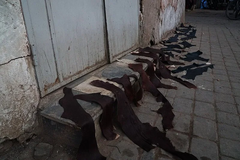 Pieles de cuero teñidas en tonos oscuros secándose en el suelo del zoco de los tintoreros de Marrakech