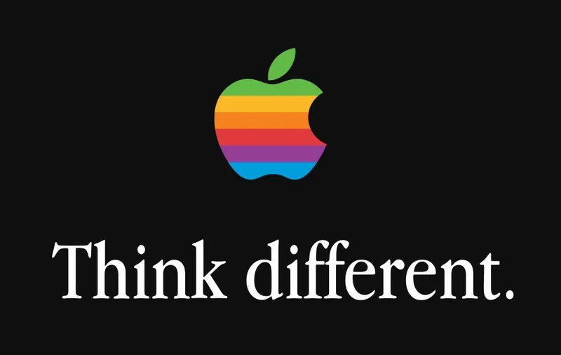 Cartel Think Different con la manzana mordida de Apple en franjas arcoíris sobre fondo negro