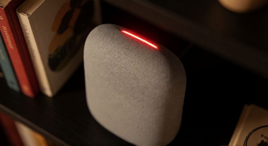 porque google home tiene una luz encendida, Nest Audio con luz roja indicando micrófono desactivado sobre una estantería de libros