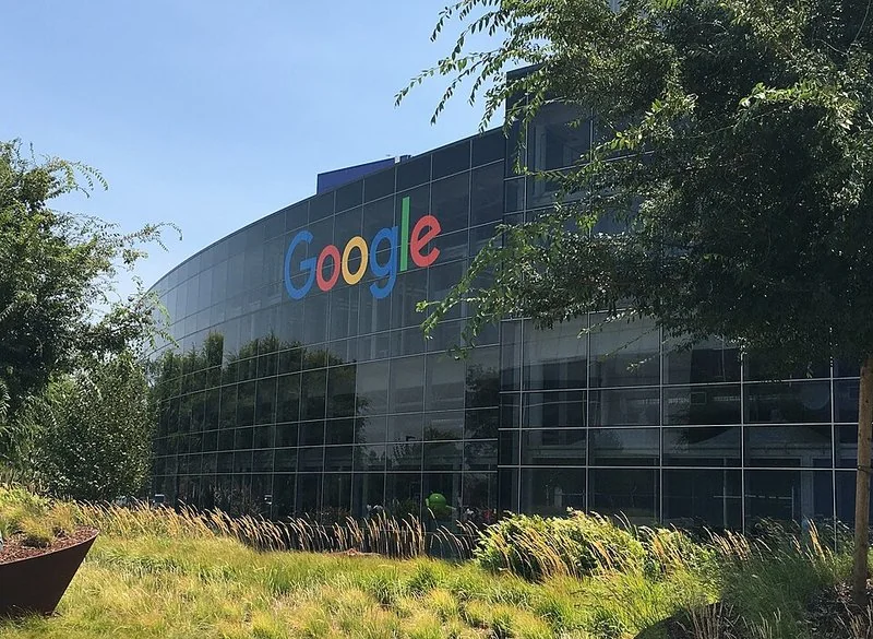porque google quito el modo ia, Edificio del logotipo de Google entre arbolado y jardines en la sede de la compañía