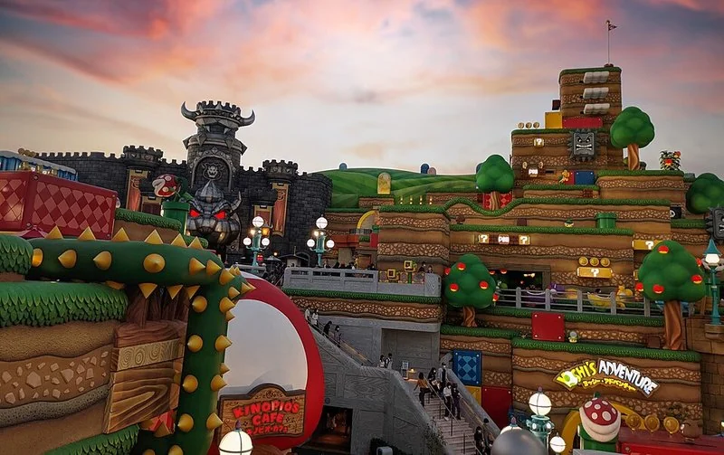 que animal es yoshi, Parque Super Nintendo World de Osaka al atardecer con la atracción Yoshi's Adventure visible