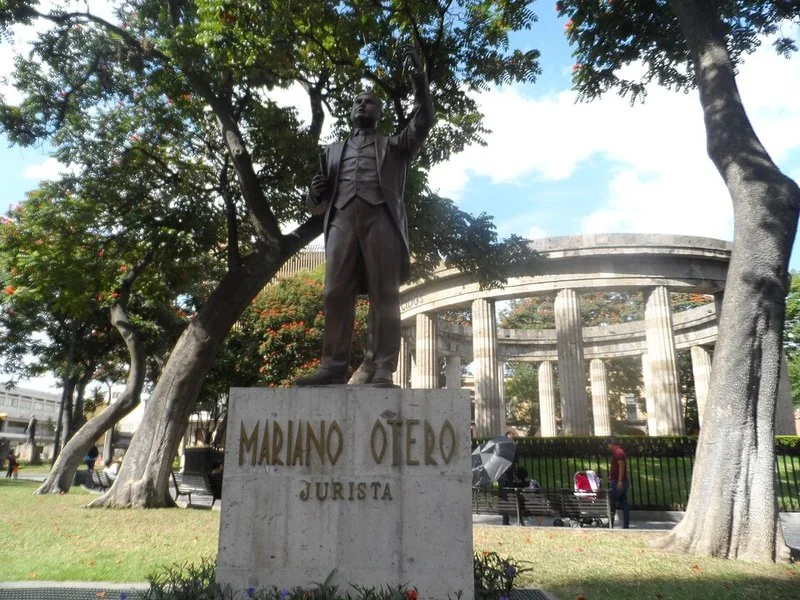 Estatua de bronce del jurista Mariano Otero sobre pedestal con su nombre, en un parque arbolado