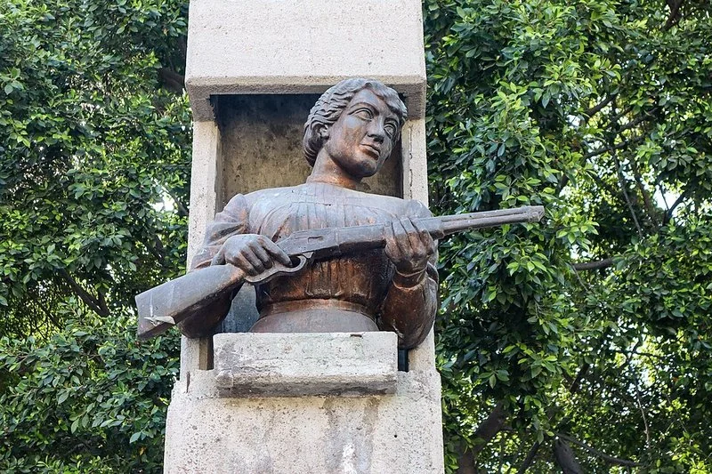 que hicieron los hermanos serdán, Monumento a Carmen Serdán en la ciudad de Puebla: busto de bronce de la revolucionaria asomado a un nicho de cantera, empuñando un fusil, en recuerdo de la aren