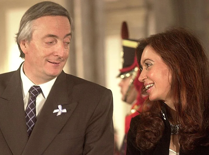 Néstor Kirchner y Cristina Fernández de Kirchner conversan sonrientes durante un acto oficial en Buenos Aires, mayo de 2004, con un guardia de honor al fondo