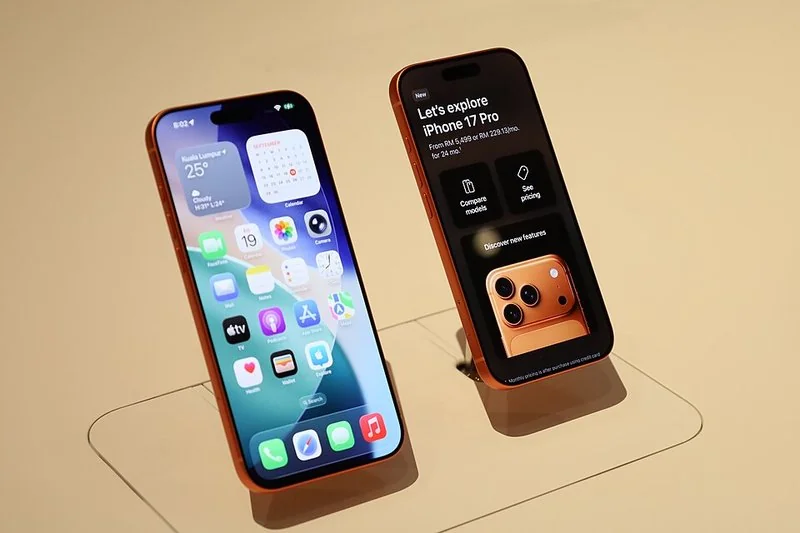 que iphone comprar en 2026, Persona sosteniendo un iPhone de gama media en una cafetería
