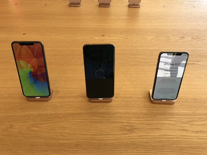 Tres iPhone X expuestos en los soportes de madera de una tienda Apple