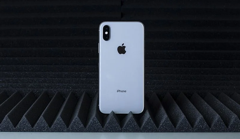 que iphone x es mejor, Parte trasera plateada de un iPhone con doble cámara vertical y logo de Apple