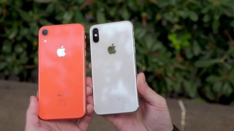 que iphone ya no se puede actualizar, Dos manos sosteniendo por la parte trasera un iPhone XR en color coral y un iPhone XS plateado, modelos lanzados en 2018 que Apple dejó fuera de las actualizaci