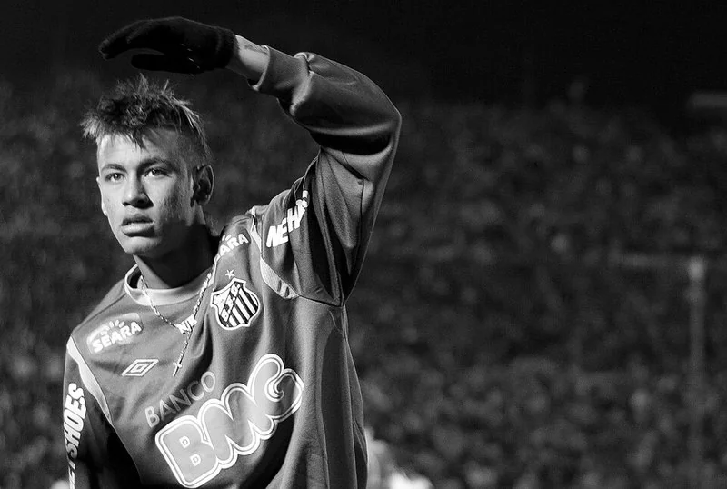 Neymar, en imagen en blanco y negro, con la camiseta del Santos F. C. (patrocinios Seara, Banco BMC y Umbro) saludando con el brazo levantado ante la grada, en 