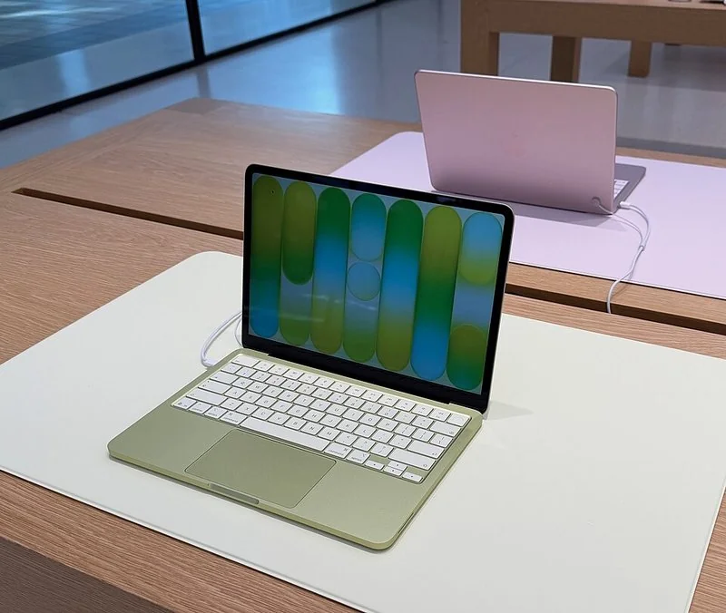 que ordenador comprar en 2026, MacBook Neo verde en exposición de tienda junto a un portátil rosa